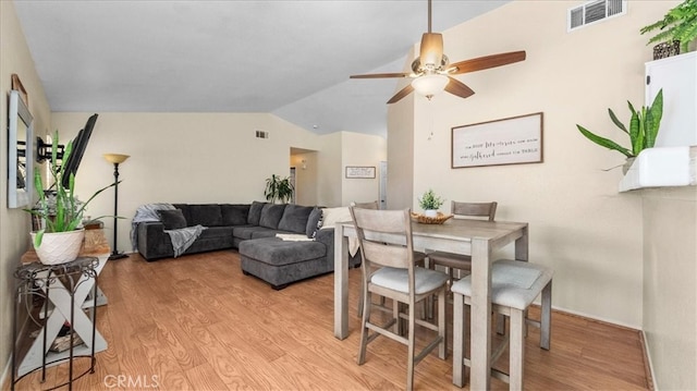 dining space featuring light wood-type flooring, visible vents, vaulted ceiling, and a ceiling fan