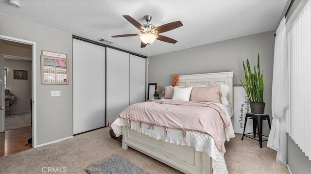 bedroom featuring a closet, visible vents, ceiling fan, and light carpet