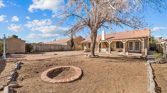 rear view of house featuring a tile roof, a patio area, a shed, a fenced backyard, and an outdoor structure