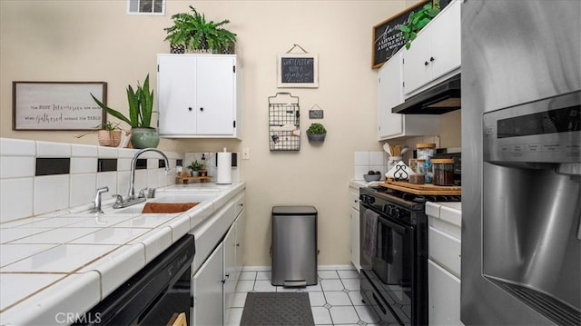 kitchen with black appliances, under cabinet range hood, tile counters, and a sink