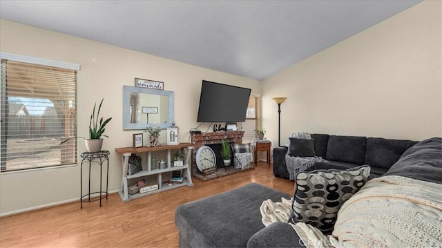 living area featuring baseboards, vaulted ceiling, and light wood finished floors