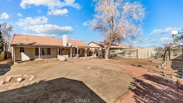 rear view of house featuring a tile roof, fence, a chimney, and a patio