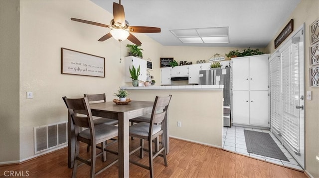 dining area with light wood-style flooring, visible vents, and a ceiling fan