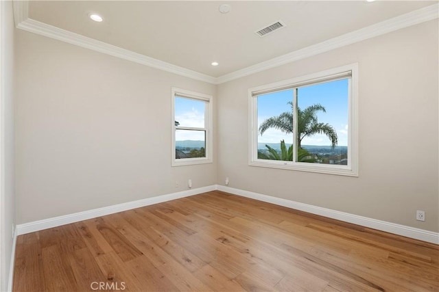 spare room featuring visible vents, baseboards, light wood-style floors, and crown molding