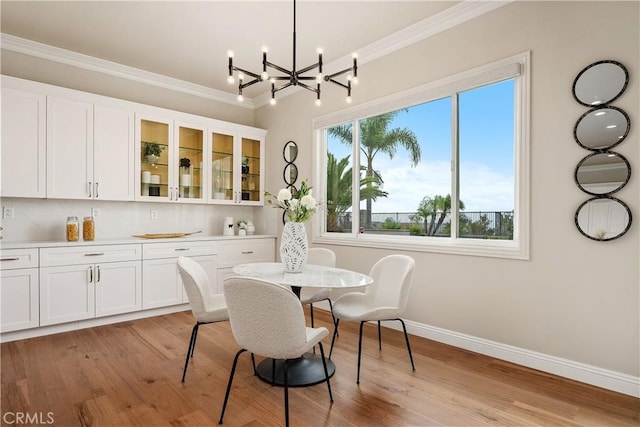 dining space featuring a notable chandelier, light wood-style flooring, crown molding, and baseboards