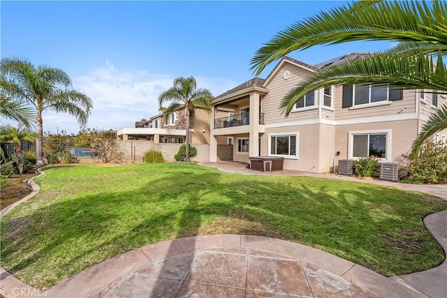 rear view of property featuring fence, cooling unit, a yard, a balcony, and a patio area