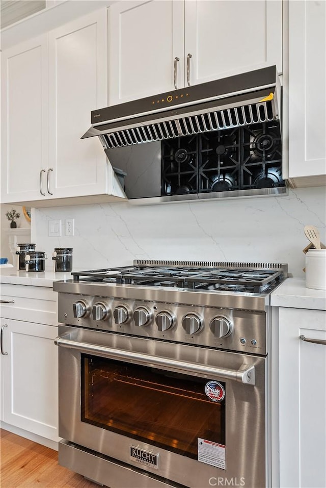 kitchen featuring tasteful backsplash, white cabinets, light countertops, and high end stainless steel range oven