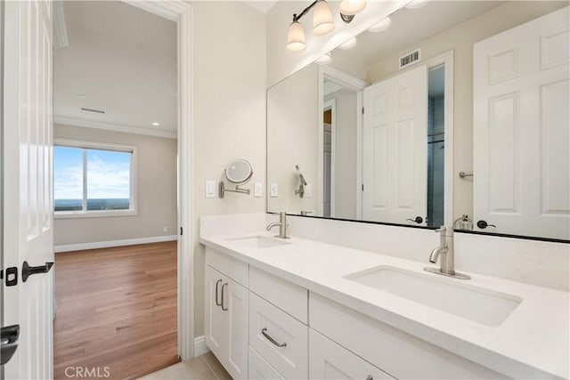 bathroom with visible vents, ornamental molding, wood finished floors, and a sink