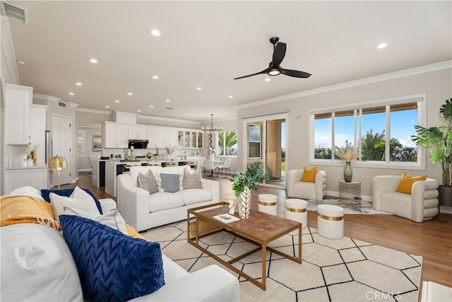 living room featuring light wood-type flooring, visible vents, recessed lighting, and crown molding