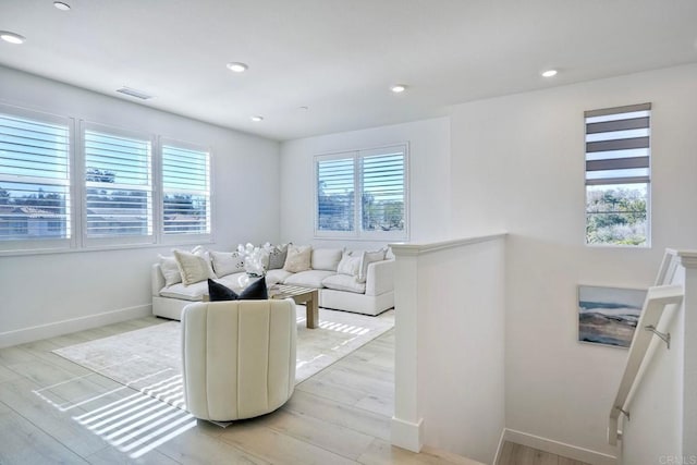 living room featuring light wood finished floors, visible vents, and a wealth of natural light