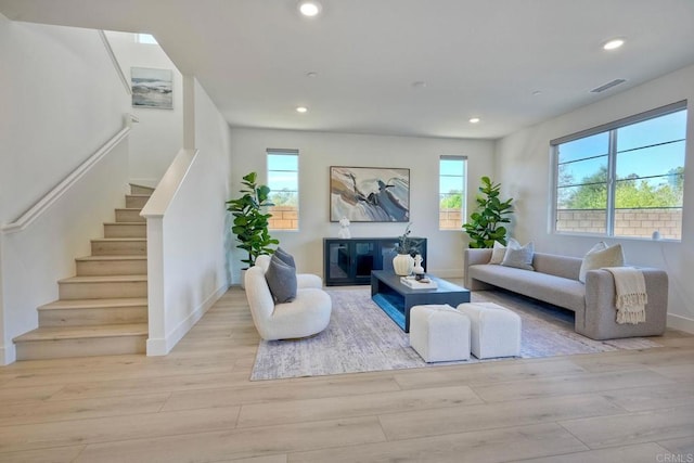 living room featuring stairway, recessed lighting, a fireplace, and light wood-style flooring