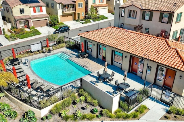 community pool with a residential view, fence, and a patio