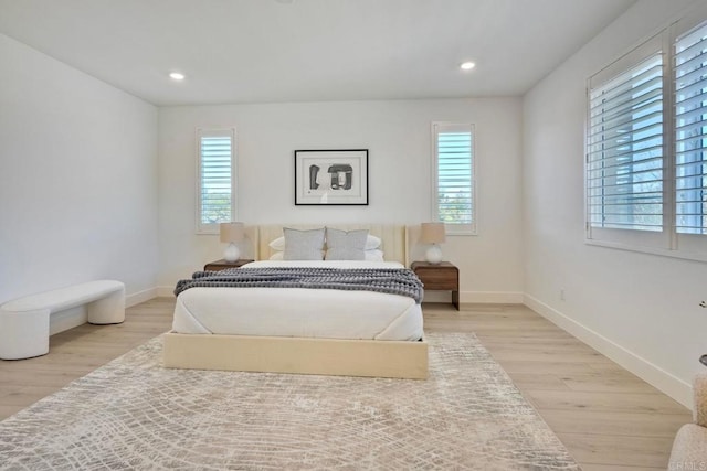 bedroom featuring light wood-type flooring, multiple windows, and baseboards