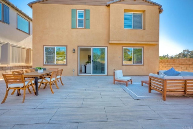 back of property featuring outdoor lounge area, a patio, fence, and stucco siding