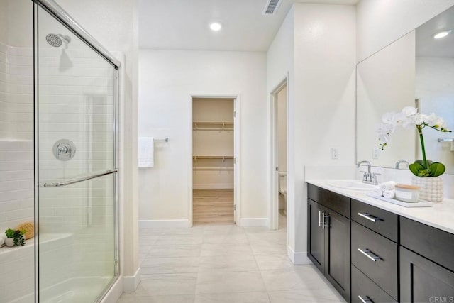 bathroom with toilet, vanity, visible vents, baseboards, and a shower stall