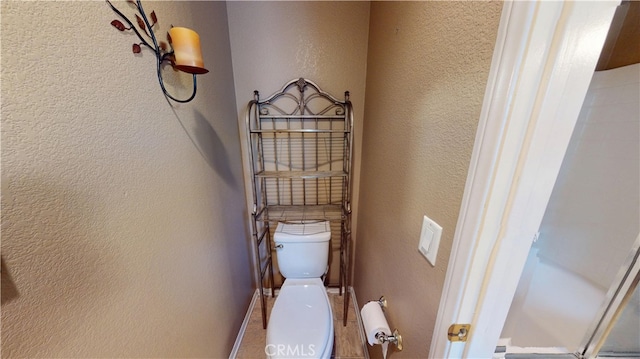 bathroom featuring a textured wall and toilet