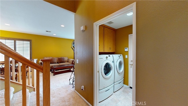 clothes washing area with visible vents, baseboards, cabinet space, and washer and dryer