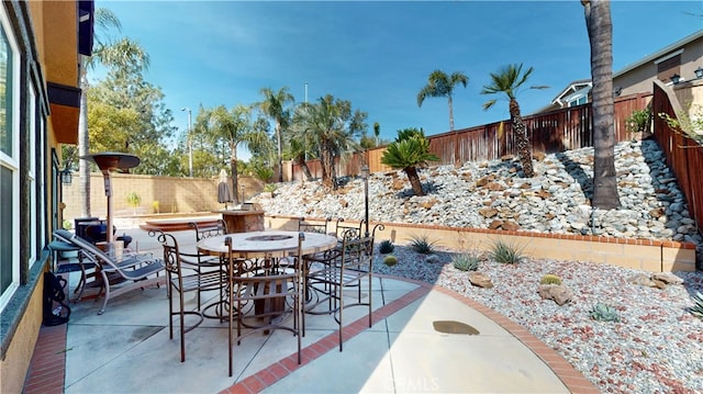 view of patio featuring outdoor dining space, a fenced backyard, and a jacuzzi