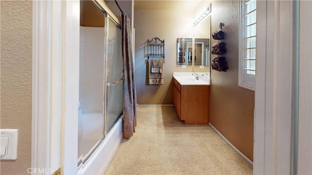 bathroom featuring enclosed tub / shower combo, a textured wall, vanity, and baseboards