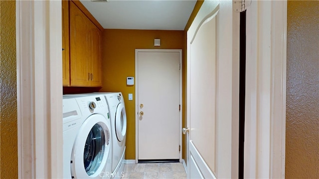 washroom featuring separate washer and dryer, cabinet space, and baseboards