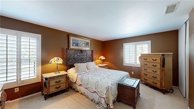 bedroom with light carpet, multiple windows, and visible vents