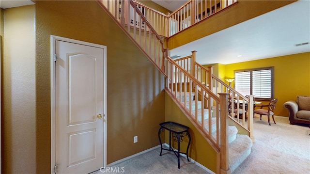 stairs featuring a high ceiling, carpet flooring, visible vents, and baseboards