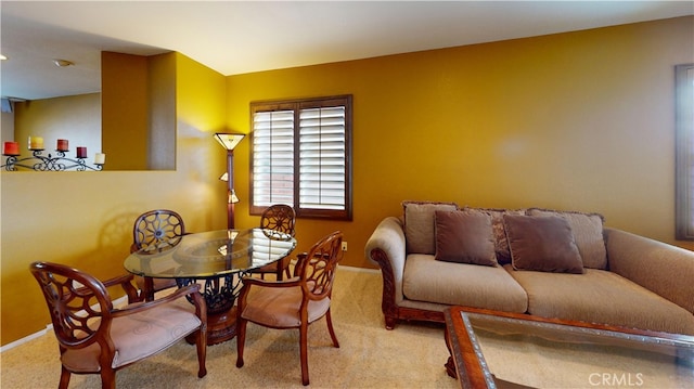 dining room featuring light colored carpet and baseboards