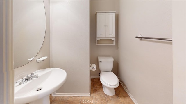 bathroom with baseboards, a sink, toilet, and tile patterned floors