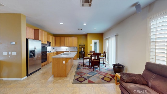 kitchen with visible vents, open floor plan, light countertops, black appliances, and an island with sink