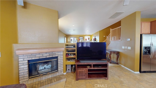 living area with stairway, a brick fireplace, visible vents, and baseboards