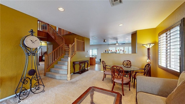 dining area with ceiling fan, recessed lighting, light colored carpet, visible vents, and stairway