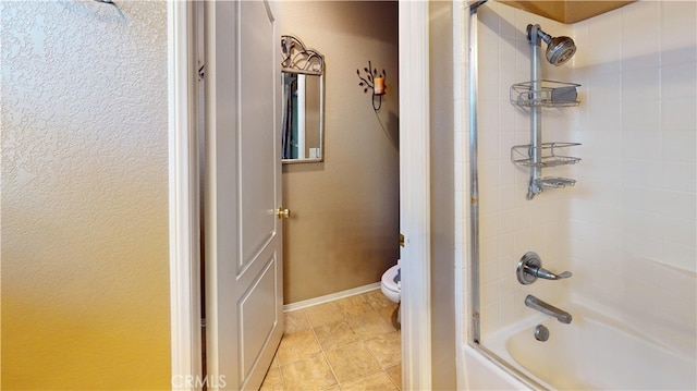 bathroom featuring toilet, baseboards, combined bath / shower with glass door, and tile patterned floors