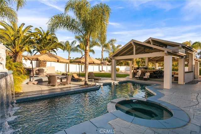 view of swimming pool featuring fence, a pool with connected hot tub, outdoor dry bar, a gazebo, and a patio area