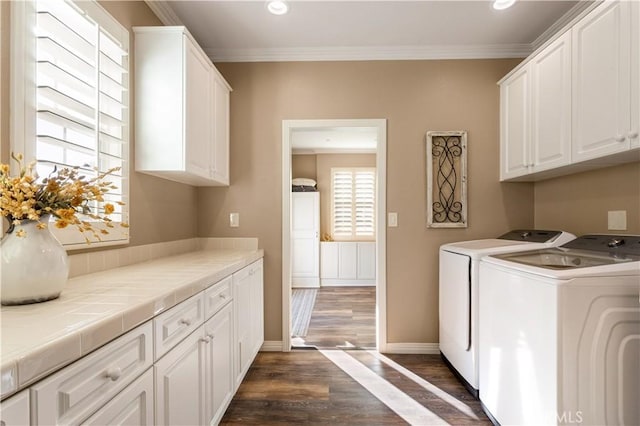 laundry room with cabinet space, dark wood-type flooring, ornamental molding, independent washer and dryer, and baseboards