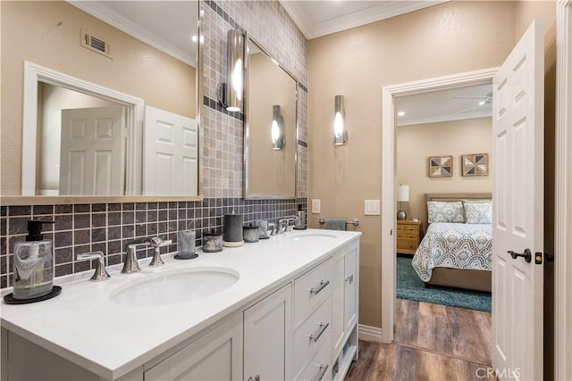 ensuite bathroom featuring crown molding, visible vents, a sink, and decorative backsplash