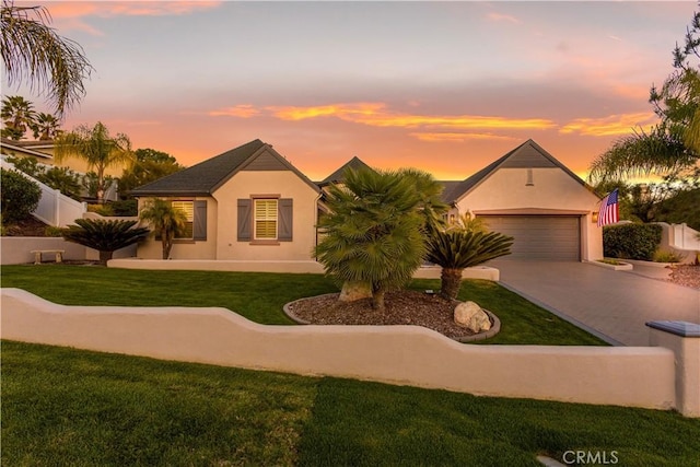 view of front of house featuring a garage, fence, concrete driveway, stucco siding, and a front yard