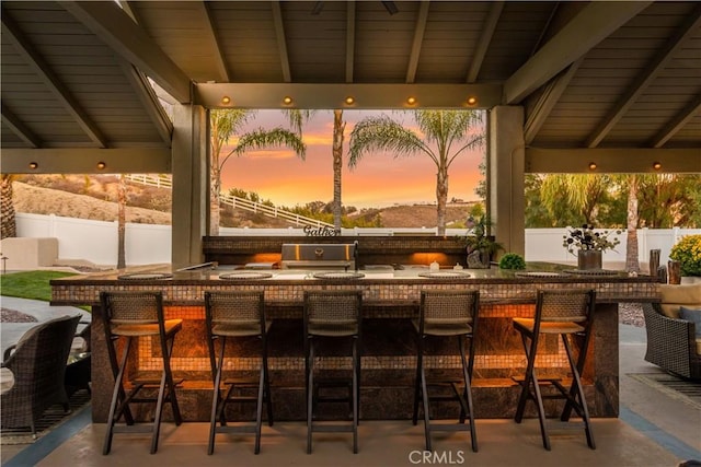 patio terrace at dusk with fence and outdoor wet bar