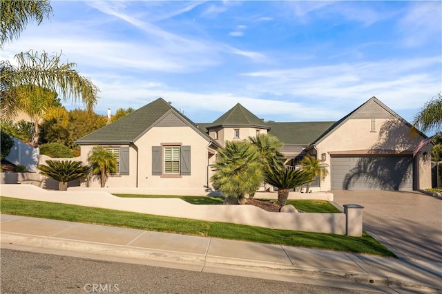 view of front of house featuring driveway, an attached garage, and stucco siding