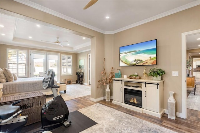 living room with a ceiling fan, a wealth of natural light, a glass covered fireplace, and light wood finished floors