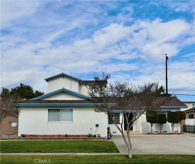 view of front of house featuring a front yard, concrete driveway, fence, and stucco siding