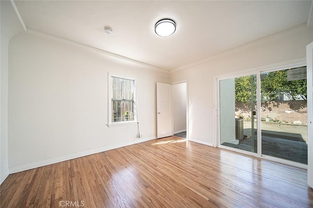 spare room with baseboards and wood finished floors