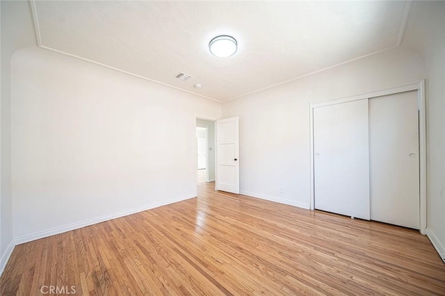 unfurnished bedroom with light wood finished floors, a closet, visible vents, and baseboards