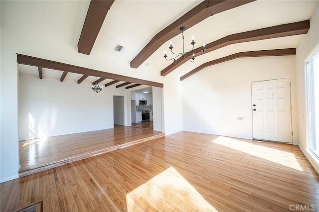 unfurnished living room with lofted ceiling with beams, a notable chandelier, a fireplace, wood finished floors, and visible vents