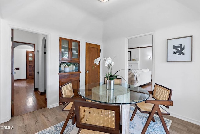 dining room with baseboards, arched walkways, and wood finished floors