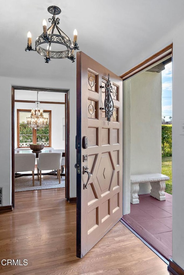 foyer with wood finished floors, a wealth of natural light, and a notable chandelier