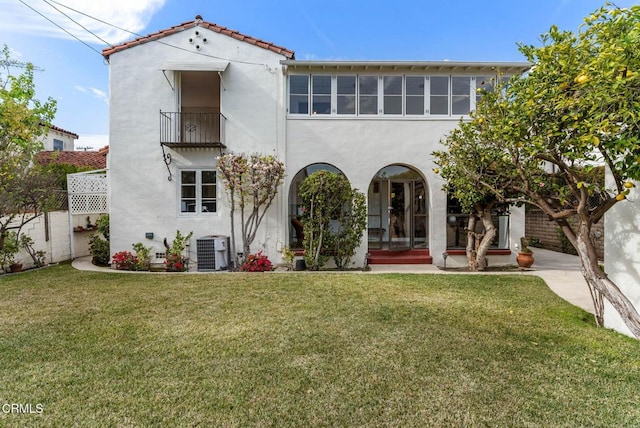 back of house with stucco siding, a lawn, central AC, fence, and a balcony