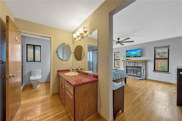 18945 Timber Point Rd, Hidden Valley Lake, CA 95467 - full bathroom with wood finished floors, toilet, a fireplace, vanity, and a ceiling fan