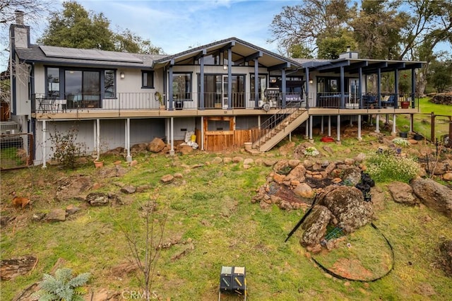 18945 Timber Point Rd, Hidden Valley Lake, CA 95467 - back of property featuring a chimney, a wooden deck, roof mounted solar panels, a sunroom, and stairs