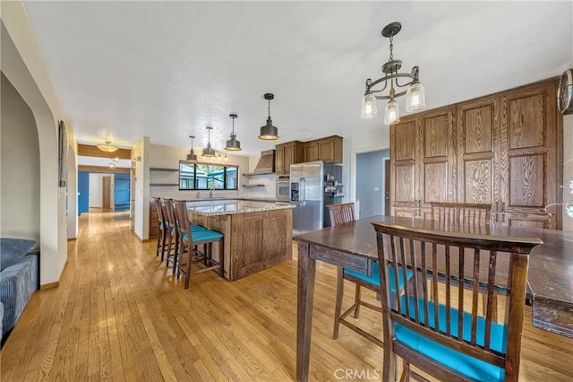 18945 Timber Point Rd, Hidden Valley Lake, CA 95467 - kitchen with brown cabinets, light wood-type flooring, a center island, wall chimney range hood, and appliances with stainless steel finishes