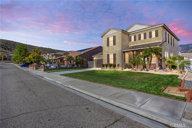 view of front of property with an attached garage, a front lawn, concrete driveway, and stucco siding